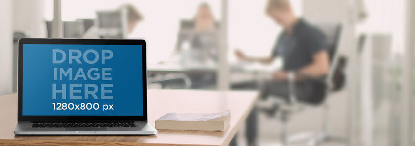 Mockup MacBook su un tavolo in un ambiente d'ufficio