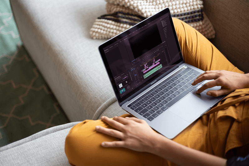 امرأة تعمل مع نموذج بالحجم الطبيعي ماك بوك يجلس على أريكة