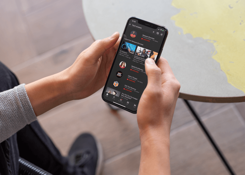 Makieta Iphone'a Xs trzymanego przez mężczyznę na zewnątrz oglądającego filmy techniczne