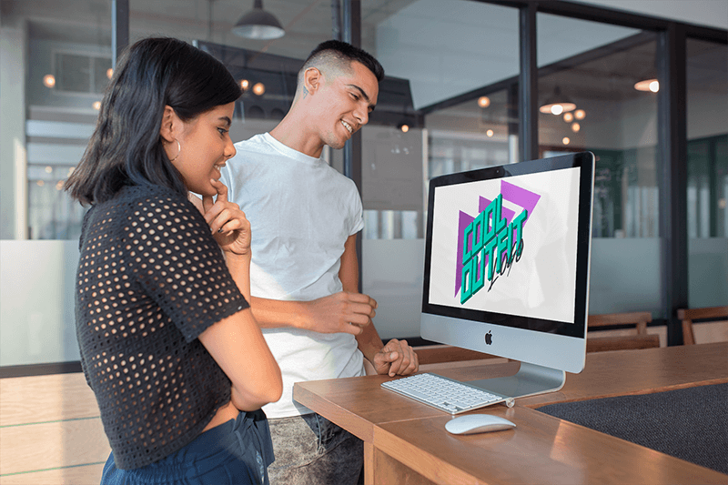 رجل وامرأة ينظران إلى نموذج بالحجم الطبيعي imac في أداة حديثة Office