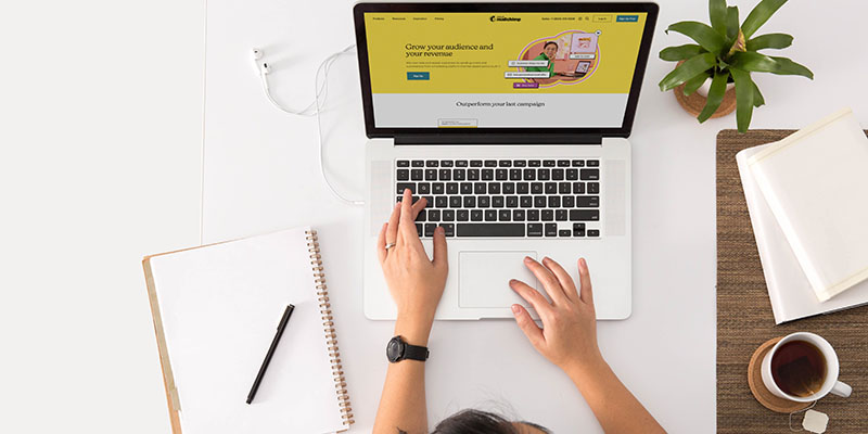 メモ帳とペンを横に置いてラップトップで入力する人