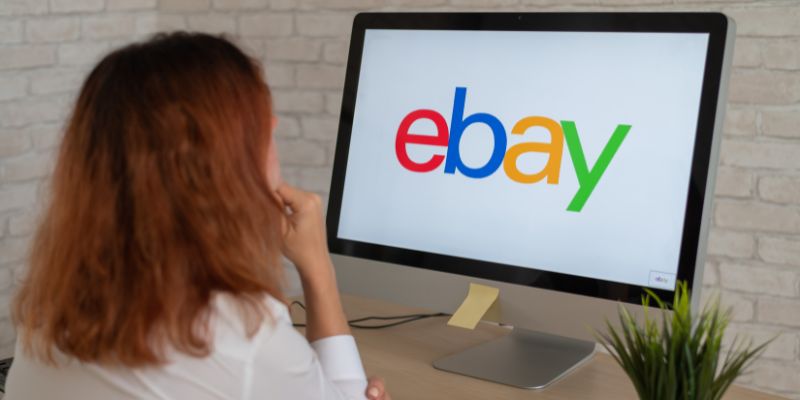 Женщина смотрит на логотип Ebay на мониторе компьютера