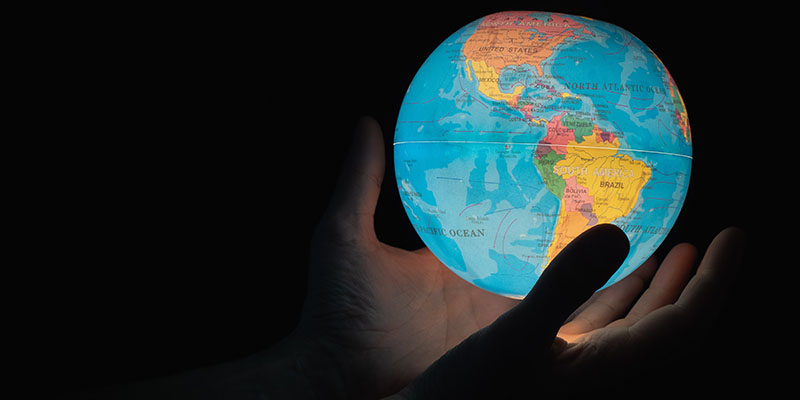 Две руки держат светящийся глобус