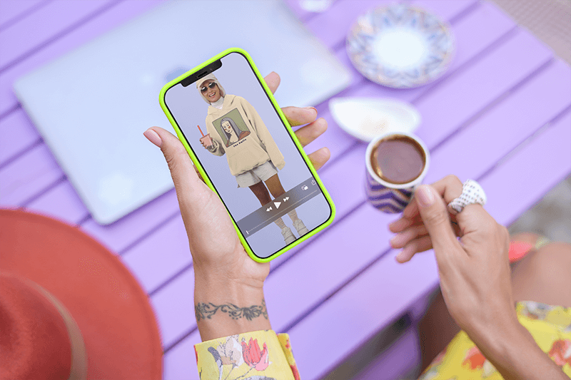 Mockup digitale di una donna con un tatuaggio al polso che tiene un Iphone 12