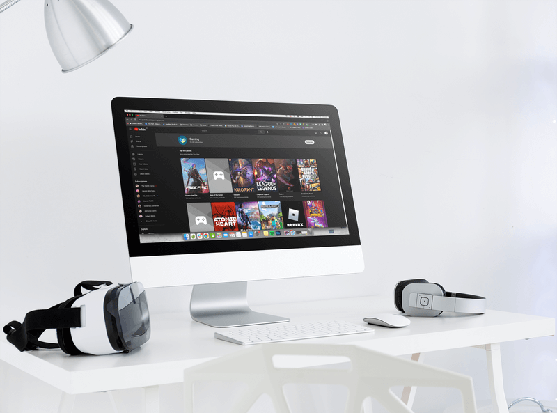 Imac Mockup mit einem Vr-Headset und einem Paar Kopfhörer auf einem Schreibtisch