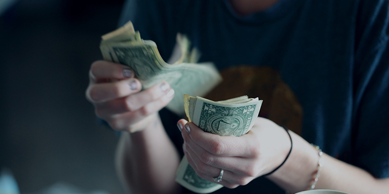 Seorang wanita berusia dua puluh empat tahun sedang menghitung uang dolar.