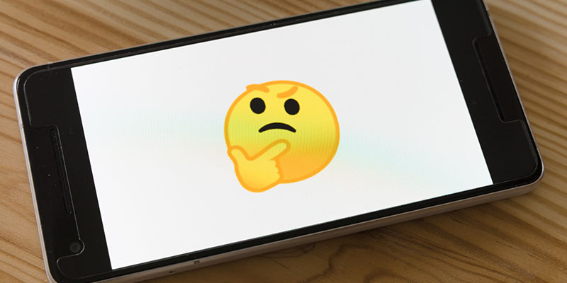 Un emoji galben gânditor pe un telefon mobil