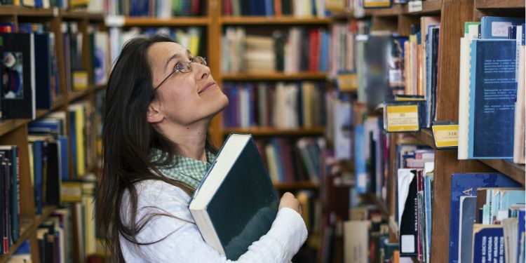 bibliotecar care se uită la un raft cu cărți