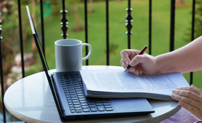 pessoa sentada em uma mesa com um computador revisando um documento