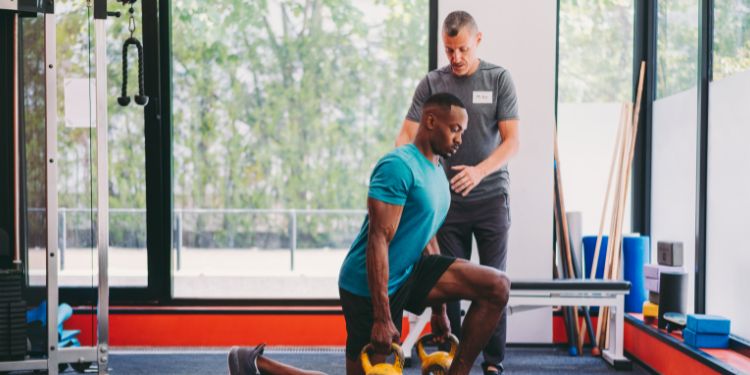 личный тренер помогает мужчине тренироваться