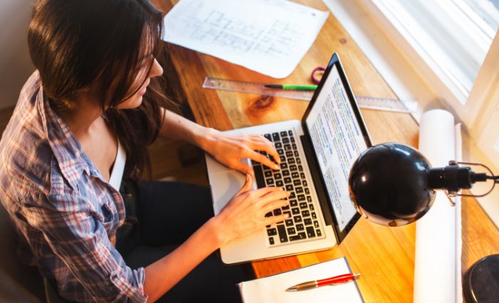 mujer escribiendo en una computadora como asistente virtual