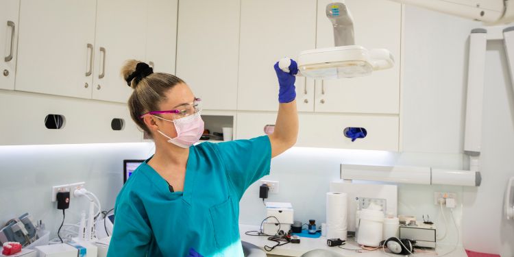 Стоматолог-гигиенист держит свет в кабинете стоматолога