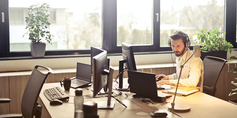 Hombre con auriculares frente a la pantalla de la computadora