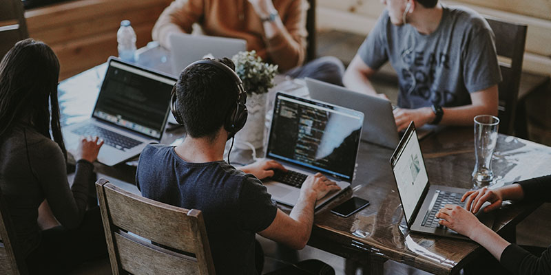 Współpracownicy z biura siedzą przy stole i odbierają połączenia