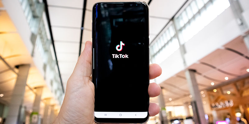 O mână care arată un telefon cu o aplicație TikTok