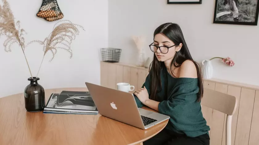 Une femme assise à une table avec un ordinateur portable réfléchit à la génération de prospects pour sa startup.