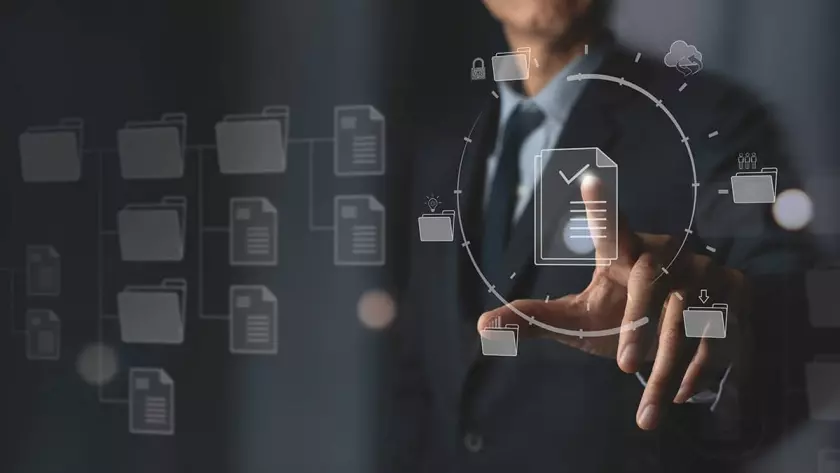 一名身穿西装的男子指着屏幕上的文档图标,正在规划自动化营销策略。