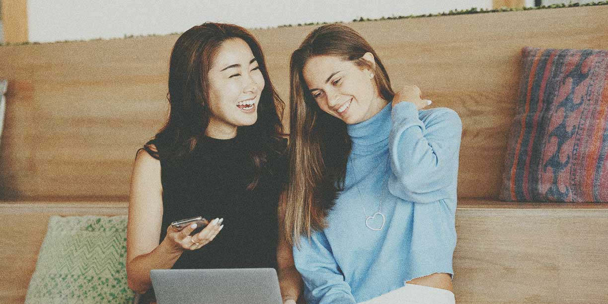 黑衣女孩向蓝衣女孩展示手机上的东西