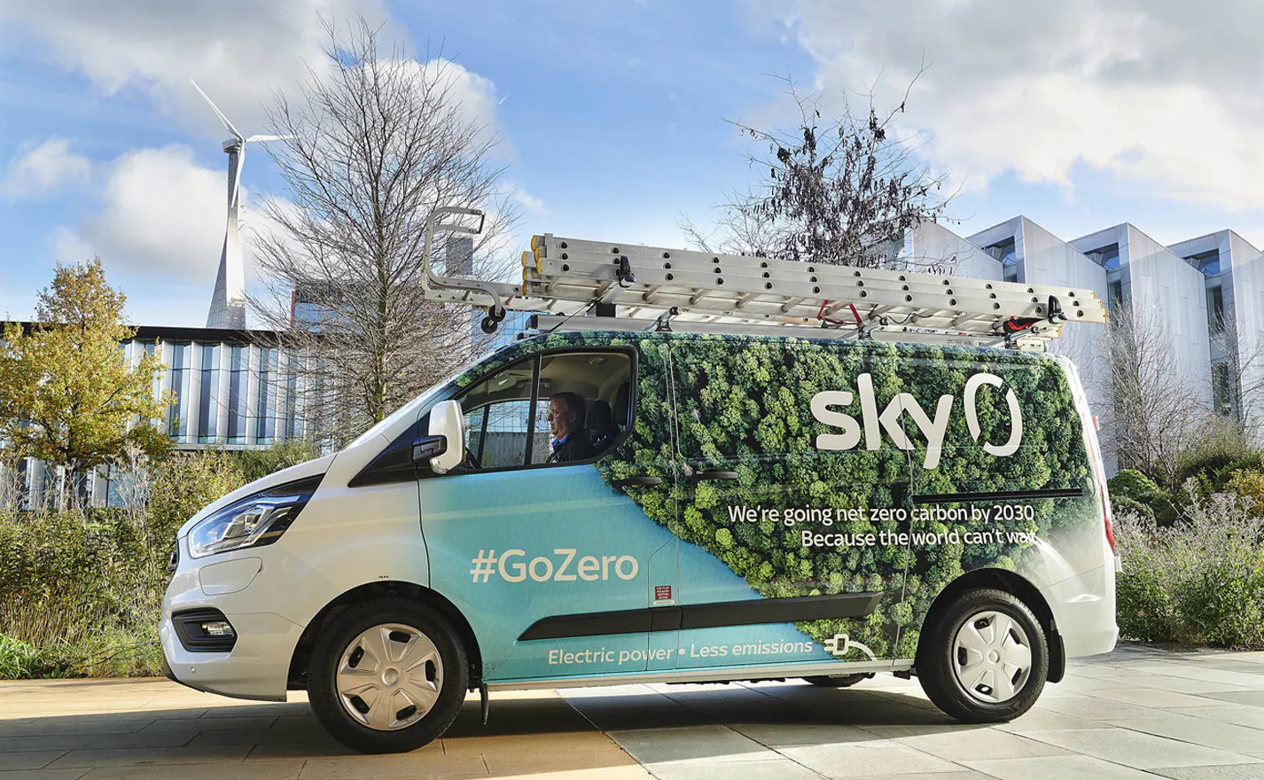 Yan tarafında ağaçlar olan bir Sky minibüsünün fotoğrafı