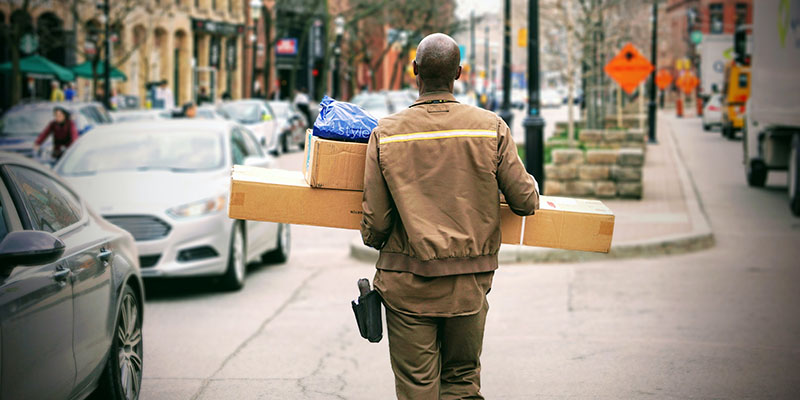 Repartidor con uniforme marrón entregando paquetes