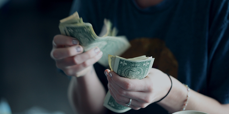 Foto close-up seorang wanita sedang menghitung uang dolar