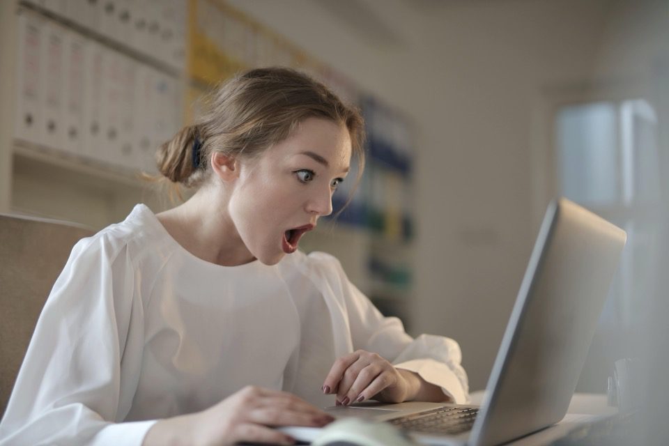 امرأة مصدومة تنظر إلى الكمبيوتر المحمول