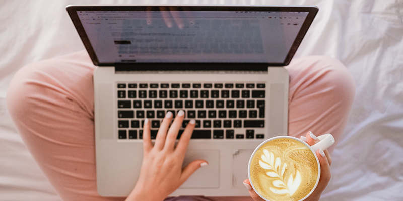 コーヒーを飲みながらノートパソコンを入力している女性