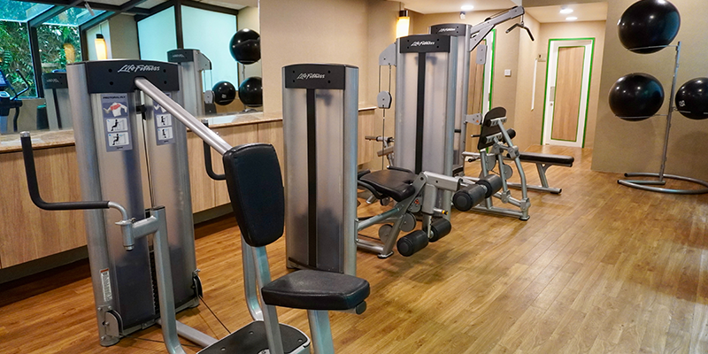 Salle de gym à domicile comprenant un tapis roulant, une presse pour jambes et des poids