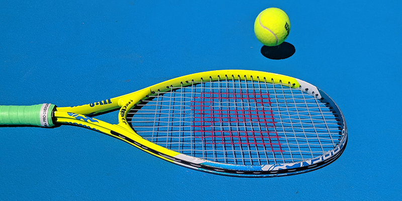 Теннисная ракетка и мяч на синем корте